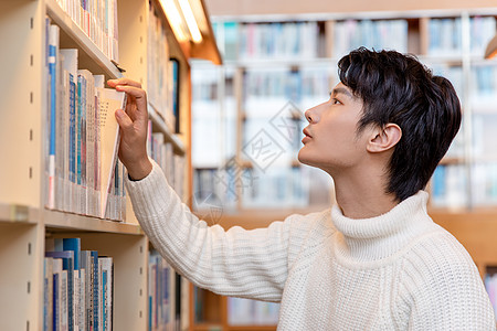 青年男性图书馆书架上寻找书籍图片