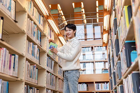 青年男性图书馆书架上寻找书籍图片