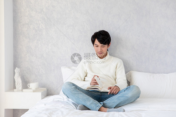 居家男性坐在床上看书学习图片