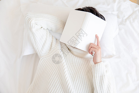 居家男性躺在床上用书盖着脸图片