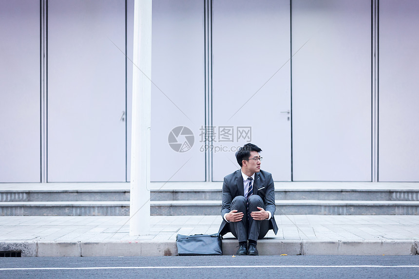 坐在路边崩溃伤心的商务男性图片