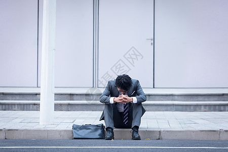 坐在路边崩溃伤心的商务男性图片