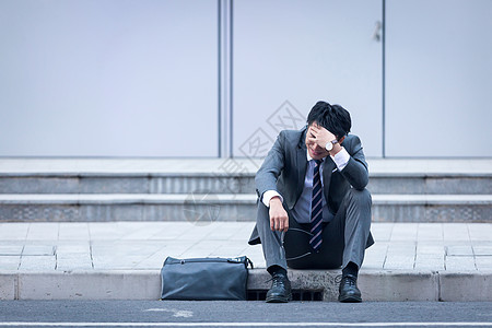 坐在路边崩溃伤心的商务男性图片