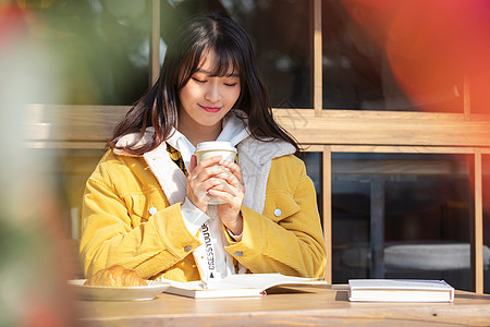 咖啡厅户外坐在咖啡厅学习的女大学生背景