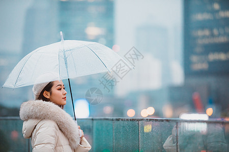 冬季女性户外下雨天撑伞看远方图片