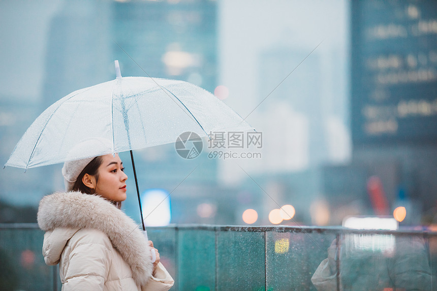 冬季女性户外下雨天撑伞看远方图片