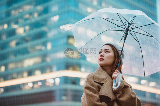 冬季女性户外下雨天撑伞看远方图片