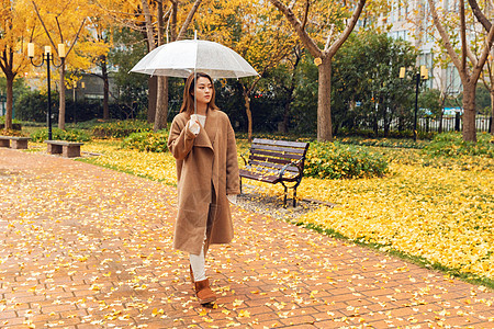 秋季雨天美女撑伞公园散步图片