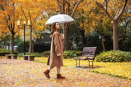 秋季雨天美女撑伞公园散步图片