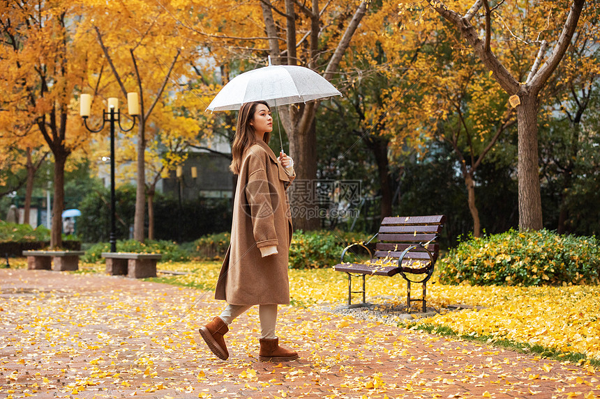 秋季雨天美女撑伞公园散步图片