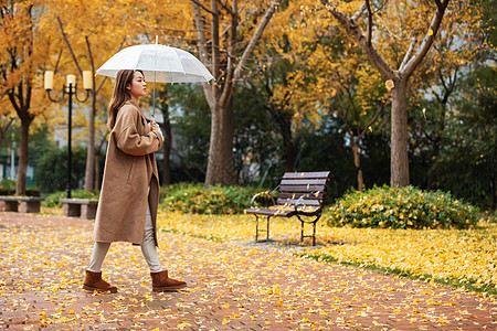 秋季雨天美女撑伞公园散步背景图片