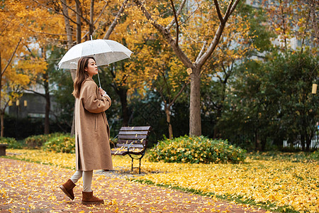 秋季雨天美女撑伞公园散步图片