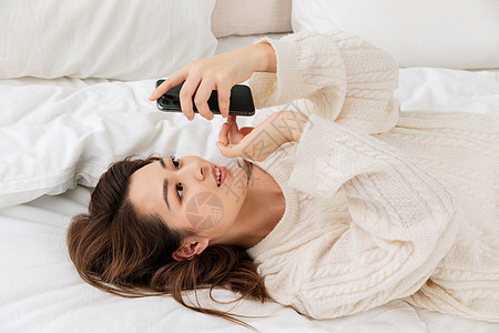 年轻女性躺床上看手机图片