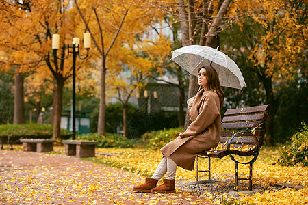 秋季雨天美女银杏落叶撑伞背景图片