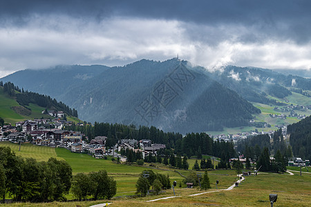 草原山脉被耶稣光照耀的意大利阿尔卑斯山下的村庄背景