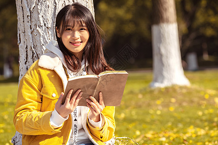 倚靠在银杏树下看书的女孩图片