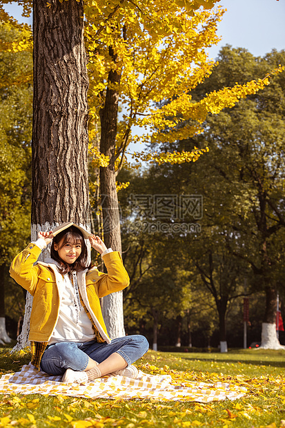 倚靠在银杏树下学习的女孩图片