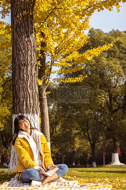 在银杏树下休息的女大学生图片