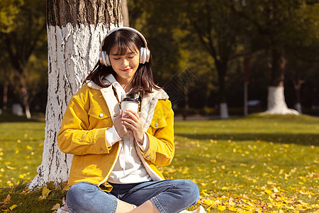 倚靠在银杏树下听音乐的女孩 图片