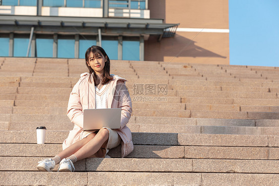 坐在学校台阶上使用电脑的女同学图片