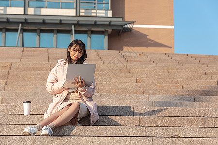 坐在学校台阶上使用电脑的女同学图片