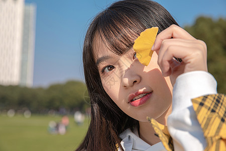 把银杏叶挡在眼前的女大学生 图片