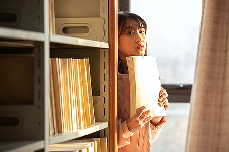 倚靠在书架边看书的女孩高清图片