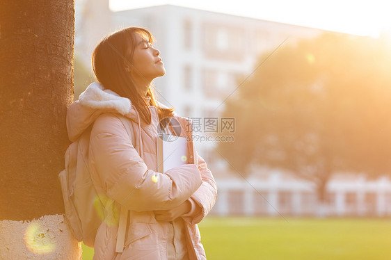 夕阳下的女大学生捧书侧影图片