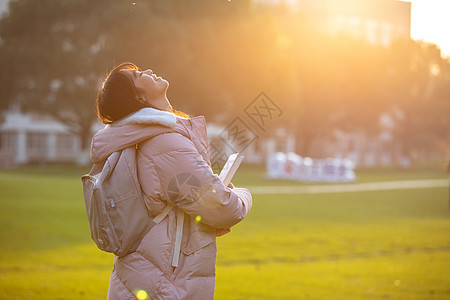 夕阳下的女大学生捧书侧影背景图片