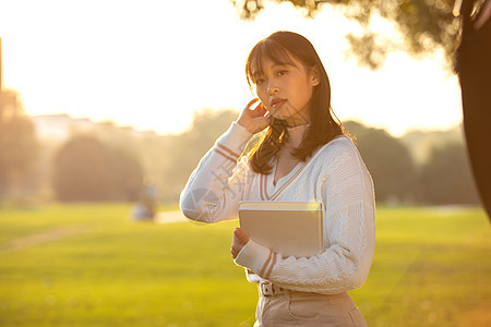 夕阳下的女大学生捧书侧影图片