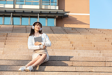 坐在台阶上听音乐的甜美女孩背景图片