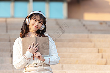 戴耳机的美女坐在台阶上听音乐的甜美女孩背景