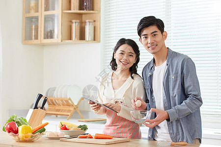 年轻夫妻拿着平板电脑学习做菜图片