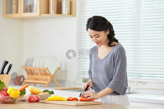 年轻女士在厨房切菜图片