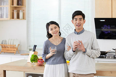 年轻情侣在厨房拿水杯喝水图片