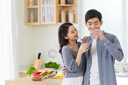 年轻情侣在厨房拿水杯喝水背景图片