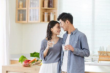 年轻夫妻在厨房手拿牛奶杯亲密拥抱图片