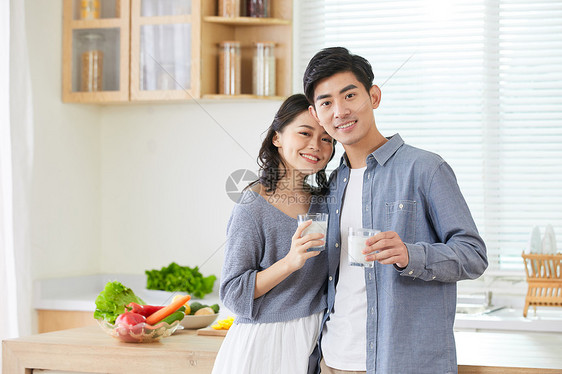 年轻夫妻在厨房手拿牛奶杯图片