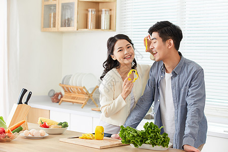 年轻情侣在厨房拿黄辣椒片互动背景图片