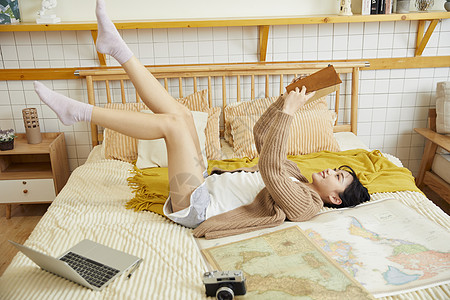张家界地图年轻女性躺在床上欣赏自己的旅行日记背景