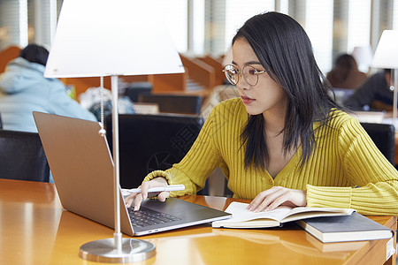 年轻女生在自习室使用笔记本电脑学习图片