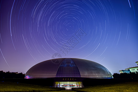 城市夜晚星空国家大剧院的星轨背景