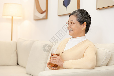 老奶奶坐沙发上手捧养生茶看电视图片