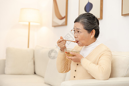 老人吃老奶奶坐沙发上喝银耳汤背景