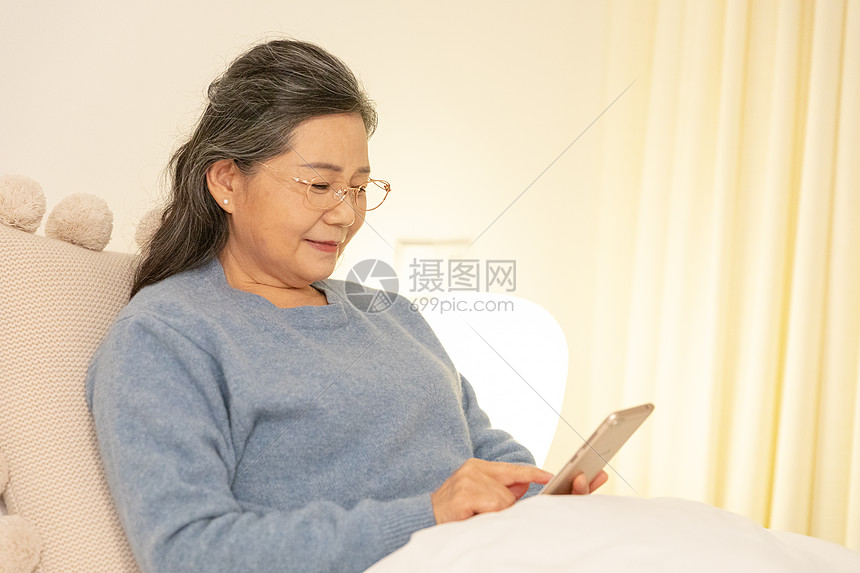 老奶奶躺在床上玩手机图片