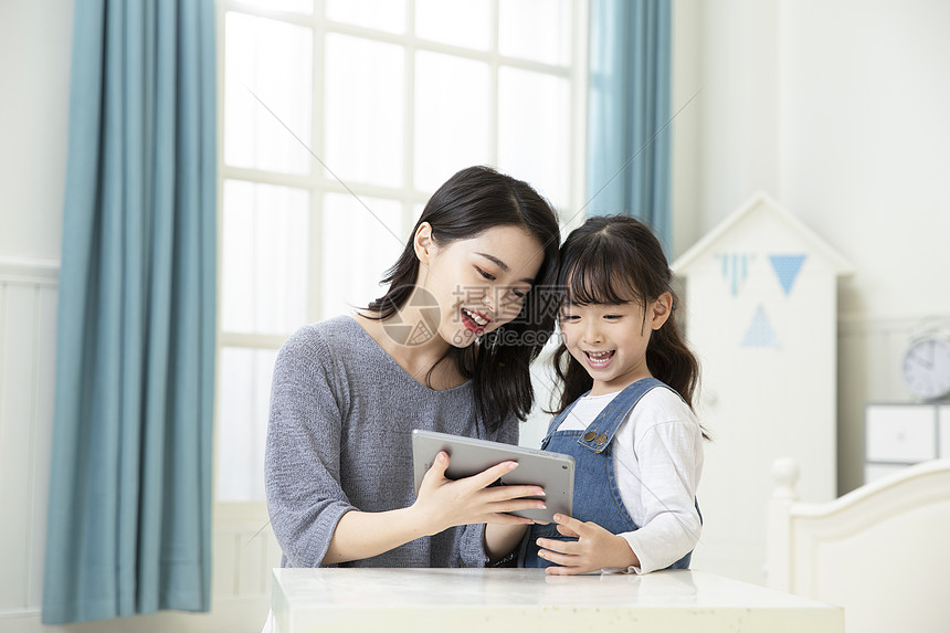 妈妈指导女儿用平板电脑在家上课图片