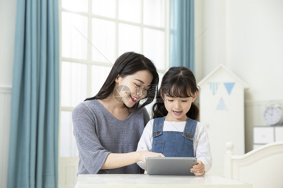 妈妈指导女儿用平板电脑在家上课图片