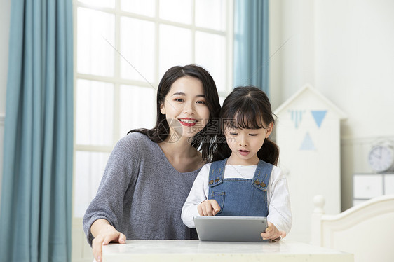 妈妈指导女儿用平板电脑在家上课图片