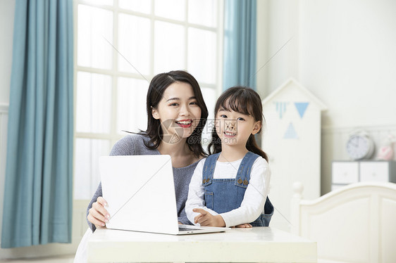 妈妈陪着女儿用笔记本电脑上网课图片