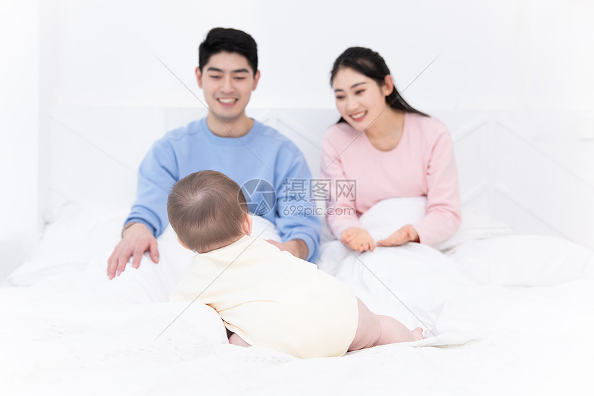 父母和婴儿一起在床上玩耍图片